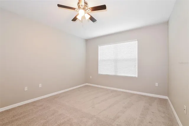 an empty room with a window and a fan