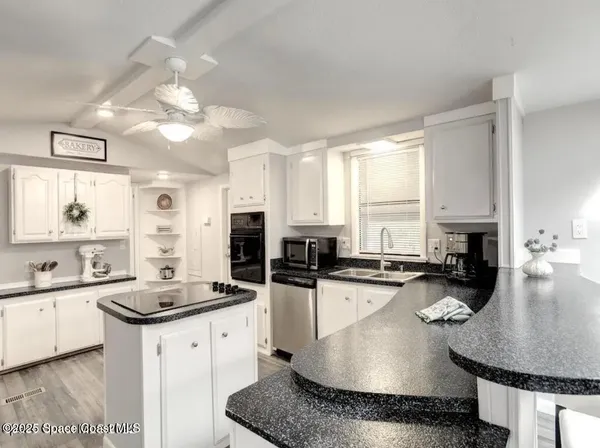 a kitchen with stainless steel appliances granite countertop a sink a stove cabinets counter space and living room view