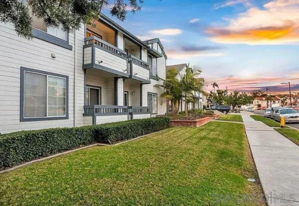 a view of a white house with a yard table and chairs