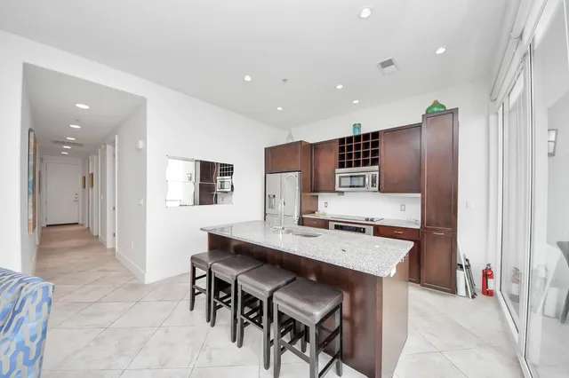 a kitchen with stainless steel appliances granite countertop a table chairs and a refrigerator