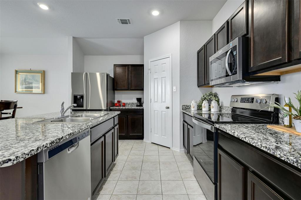 1045 Taggart Trail Jarrell, TX 76537 - Photo 4 of 19 Kitchen with stainless steel appliances, dark brown cabinetry, light stone countertops, light tile patterned floors, and recessed lighting