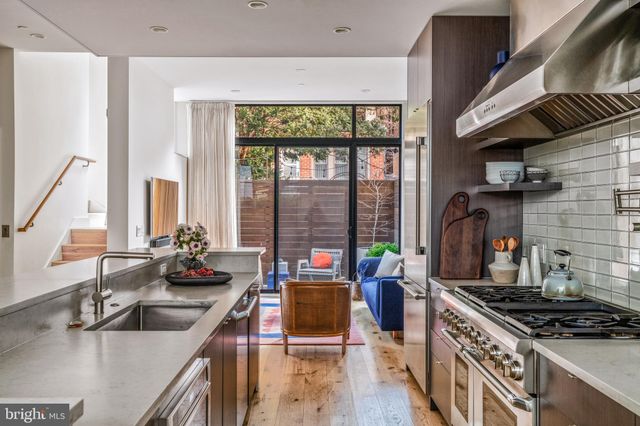 a living room with furniture floor to ceiling windows and wooden floor