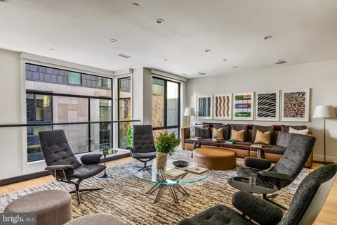 a living room with furniture floor to ceiling windows and wooden floor