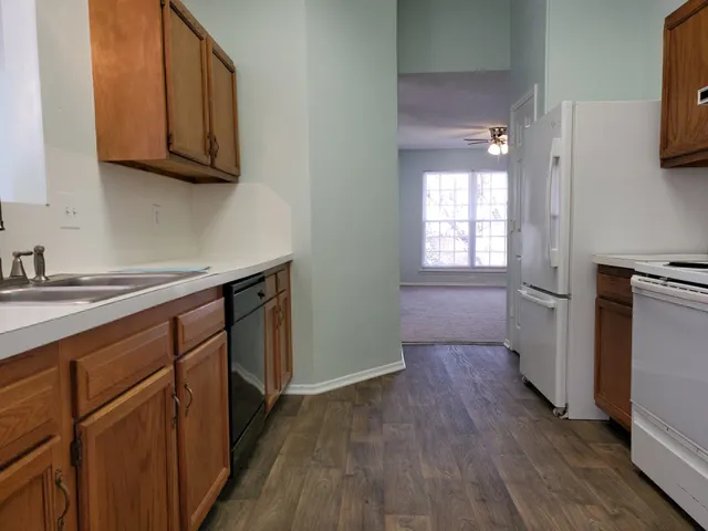a kitchen with granite countertop wooden floors and white stainless steel appliances