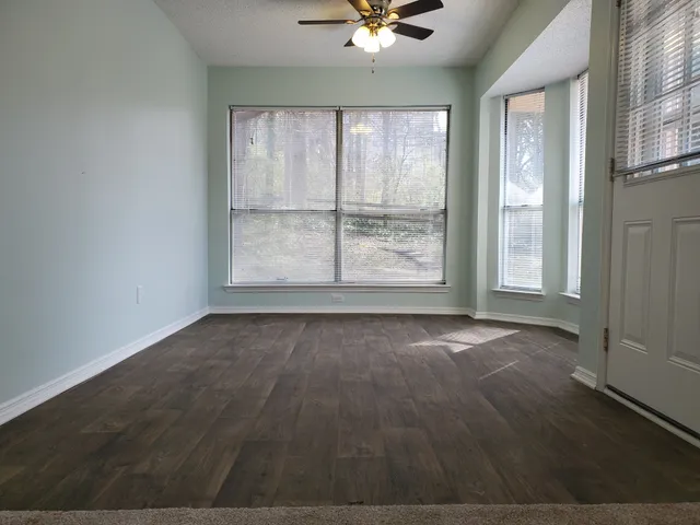 an empty room with wooden floor and windows