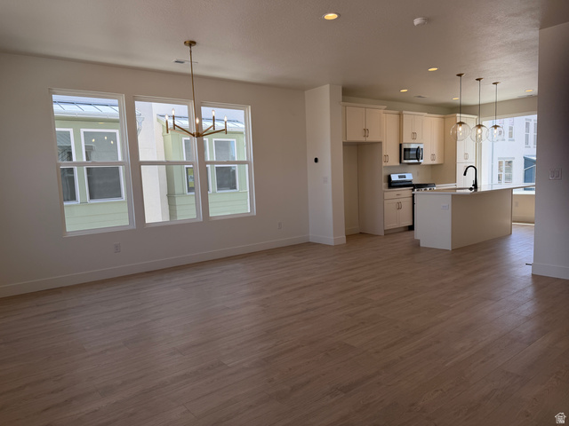 10995 South Freestone Road, Unit 109 South Jordan, UT 84009 - Photo 6 of 20 Kitchen featuring a chandelier, a center island with sink, dark wood-style flooring, and stainless steel appliances