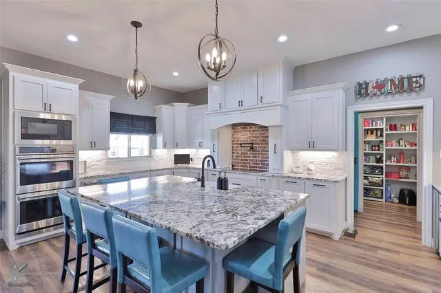 a kitchen with granite countertop stainless steel appliances and wooden floor