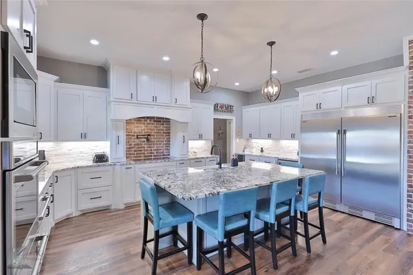 a kitchen with granite countertop a center island a sink stainless steel appliances and cabinets
