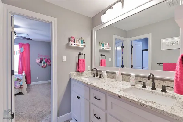a bathroom with a granite countertop double vanity sink and a mirror