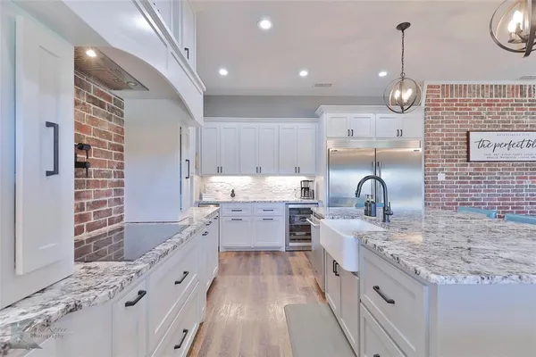 a large kitchen with granite countertop a sink a counter top space a stove and cabinets