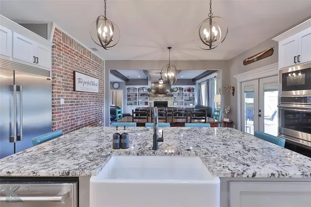 a kitchen with stainless steel appliances granite countertop a sink a refrigerator and wooden cabinets