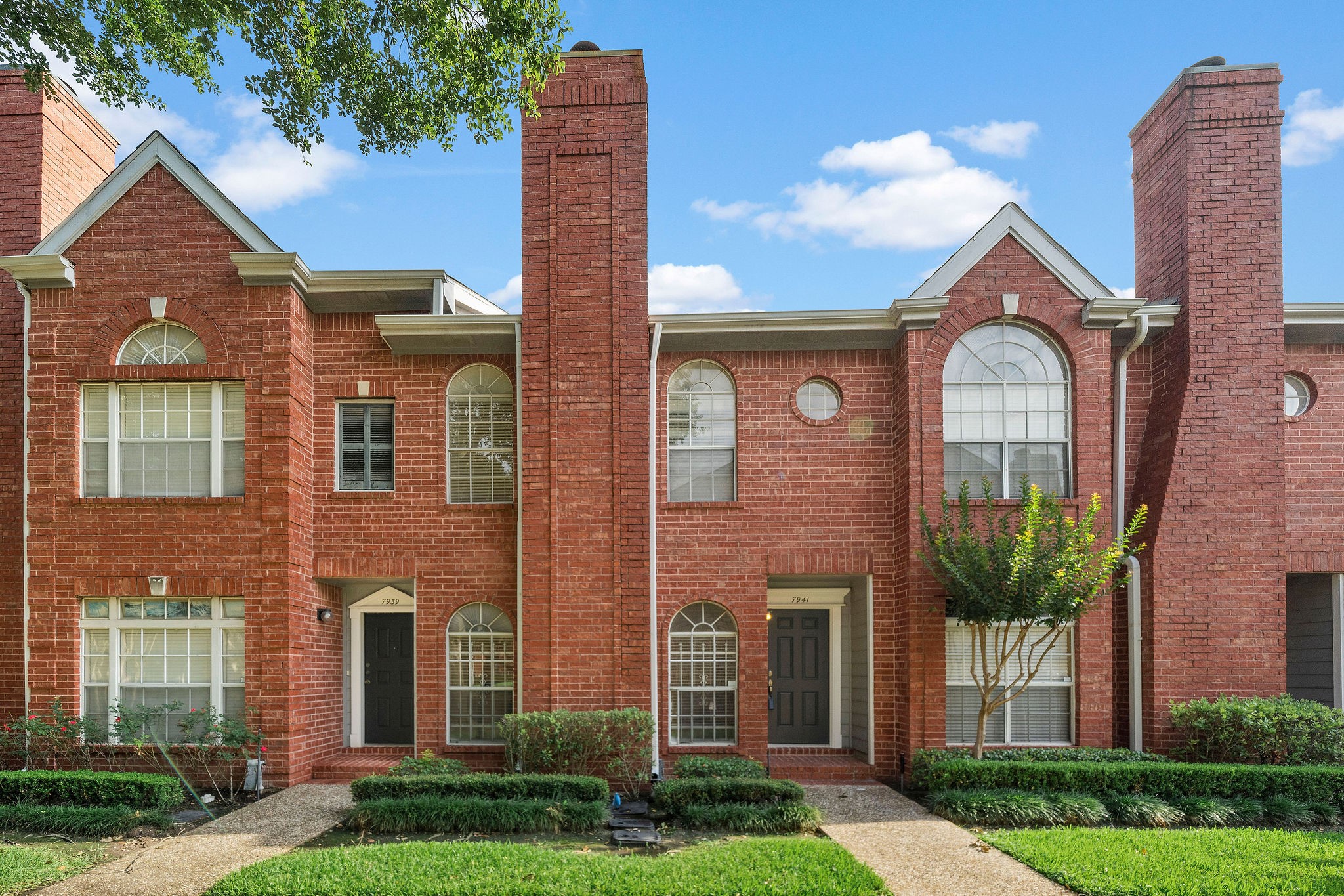 Elegant brick townhome featuring timeless architecture, soaring chimneys, and charming arched windows in a gated community near the Texas Medical Center.