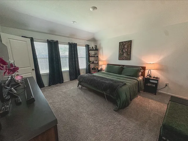 a bedroom with a bed painting on wall and a potted plant
