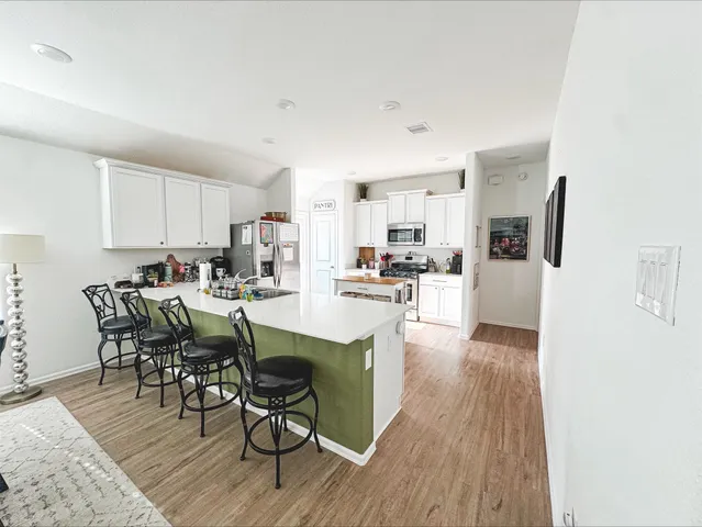 a kitchen with stainless steel appliances granite countertop a refrigerator a stove top oven a sink dishwasher and white cabinets with wooden floor
