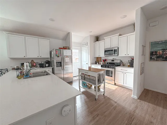 a kitchen with a sink a stove a refrigerator cabinets and a dining table