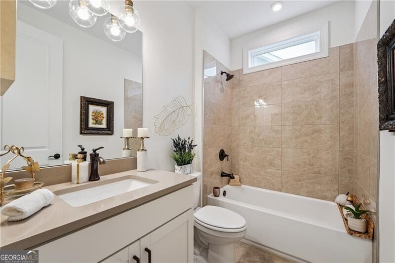 103 Rabun Court Hoschton, GA 30548 - Photo 15 of 22 a bathroom with a granite countertop sink a toilet a mirror a bathtub and shower