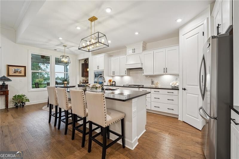 103 Rabun Court Hoschton, GA 30548 - Photo 7 of 22 a kitchen with kitchen island granite countertop a center island a refrigerator and a dining table