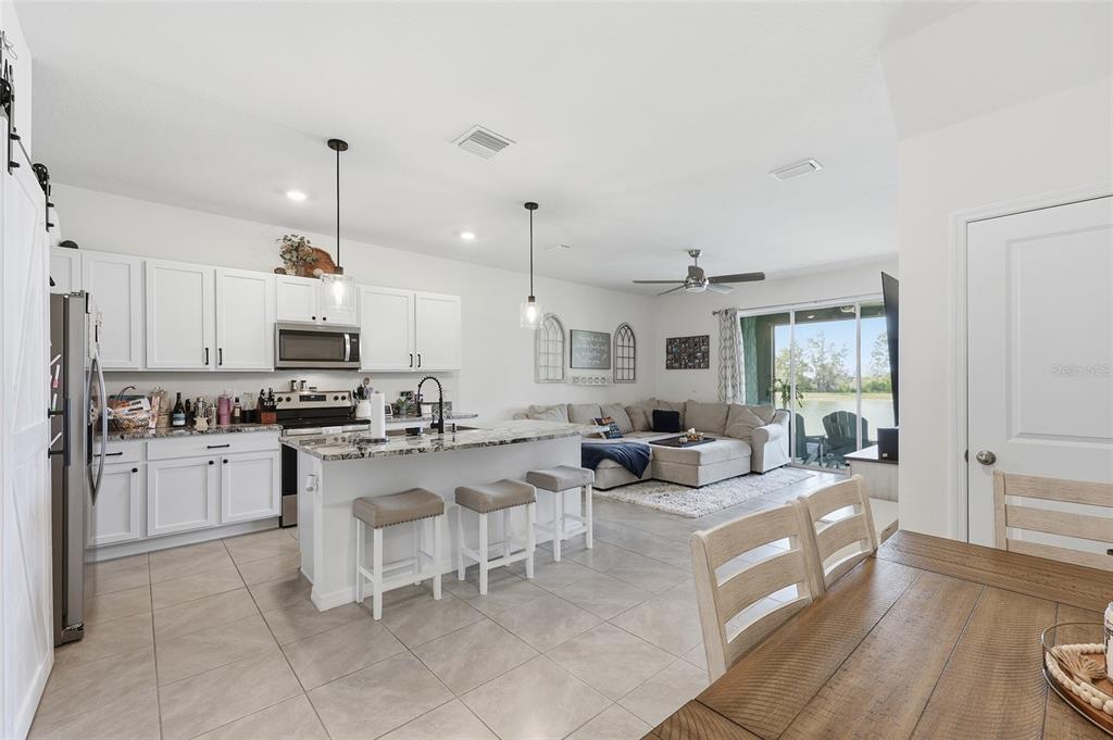 32992 Major Oak Drive Wesley Chapel, FL 33545 - Photo 5 of 56 a living room with stainless steel appliances kitchen island granite countertop furniture and a wooden floor