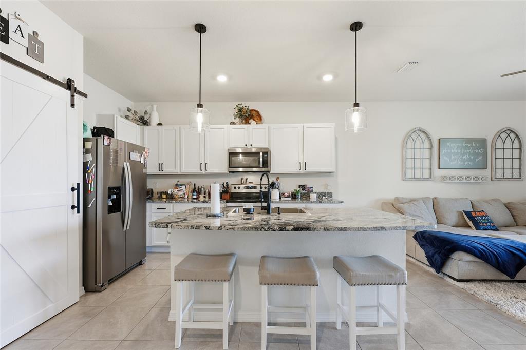 32992 Major Oak Drive Wesley Chapel, FL 33545 - Photo 6 of 56 a kitchen with kitchen island a refrigerator a sink and chairs