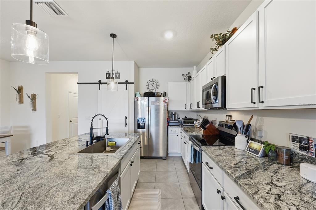 32992 Major Oak Drive Wesley Chapel, FL 33545 - Photo 7 of 56 a kitchen with stainless steel appliances granite countertop a sink dishwasher stove and refrigerator