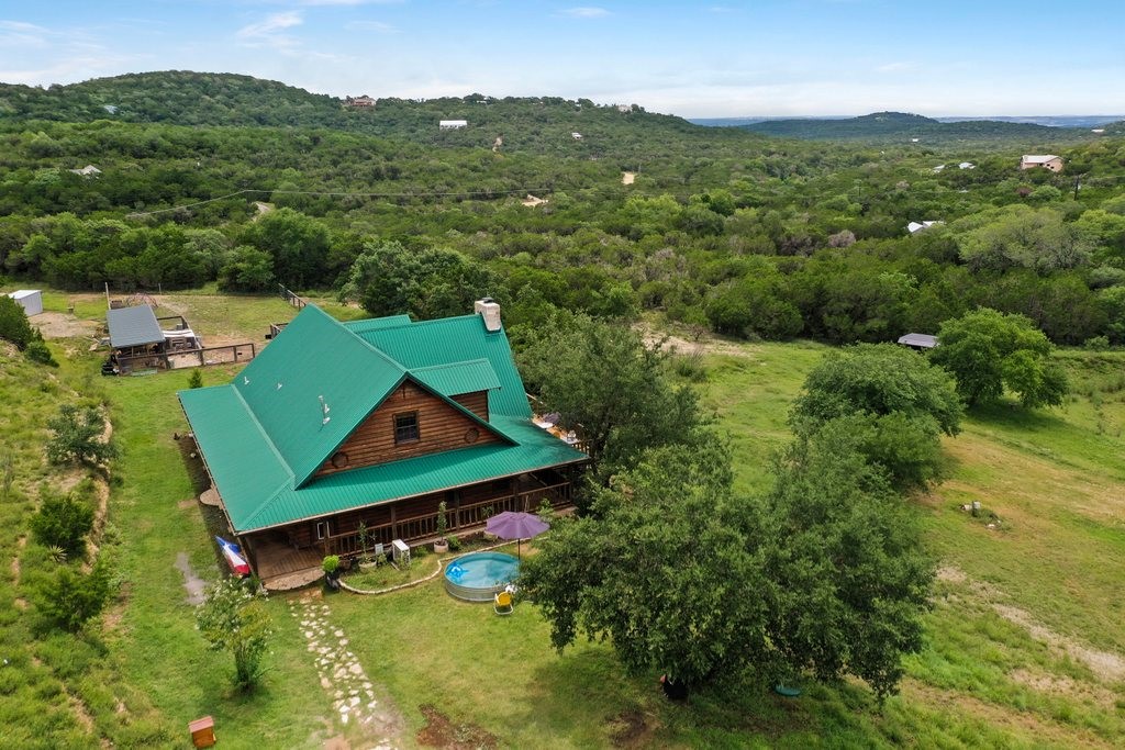 an aerial view of a houses with a lush green hillside