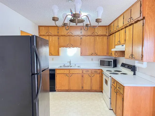 a kitchen with stainless steel appliances granite countertop a sink a refrigerator and a stove