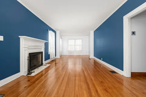 a view of empty room with wooden floor and fireplace
