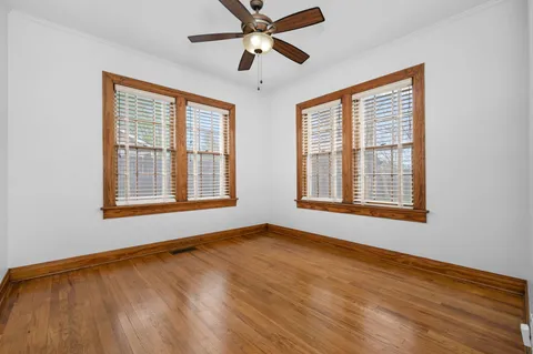 a view of an empty room with chandelier fan and a window