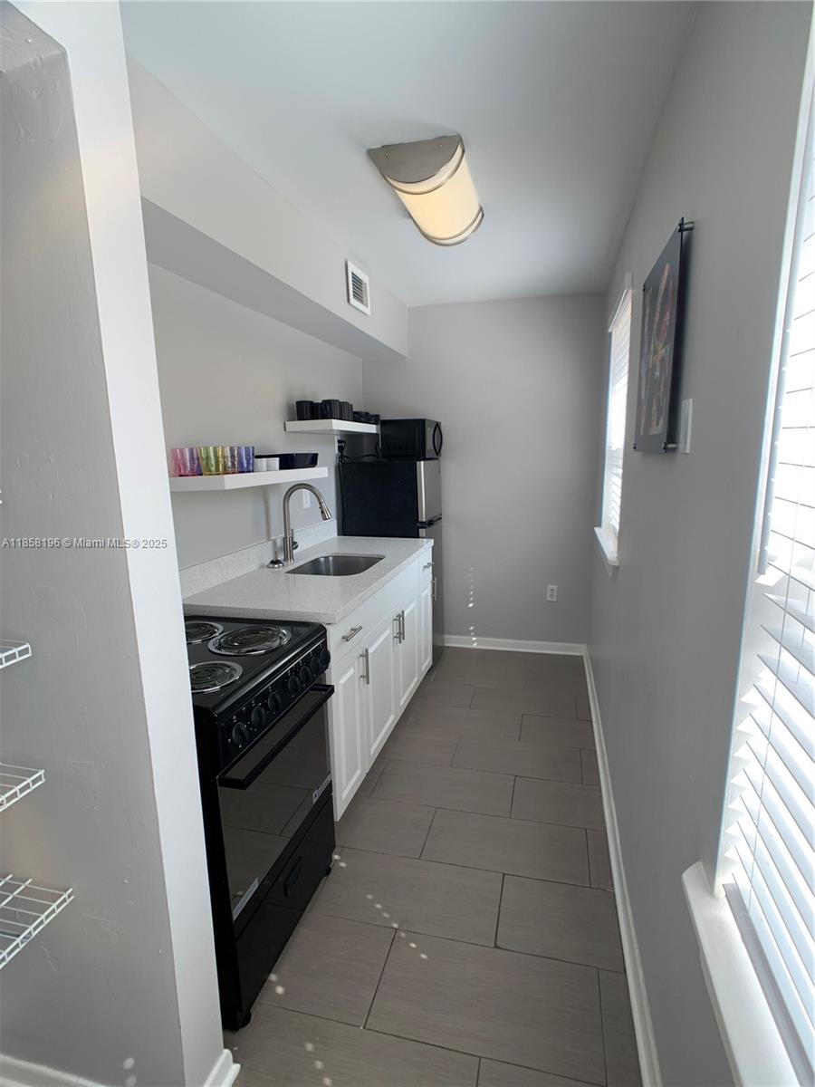 1308 Drexel Avenue, Unit 105 Miami Beach, FL 33139 - Photo 18 of 24 a kitchen with stainless steel appliances a stove a sink and a refrigerator