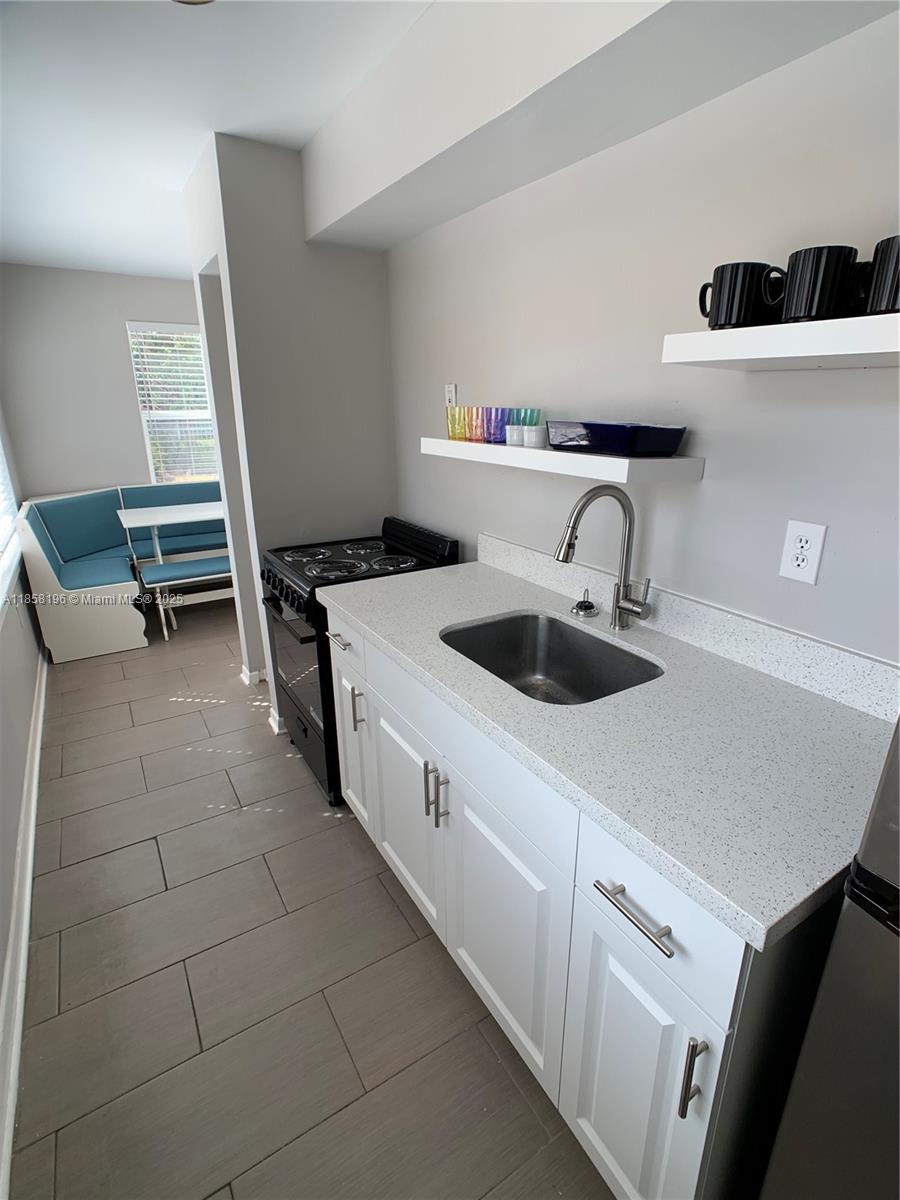 1308 Drexel Avenue, Unit 105 Miami Beach, FL 33139 - Photo 20 of 24 a kitchen with a sink a stove and white cabinets