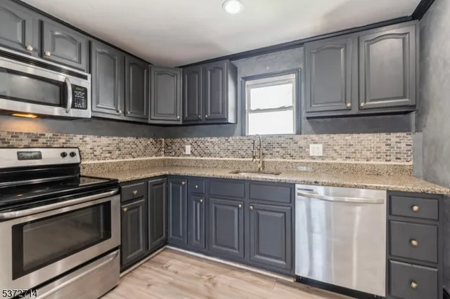 a kitchen with granite countertop cabinets stainless steel appliances and a sink
