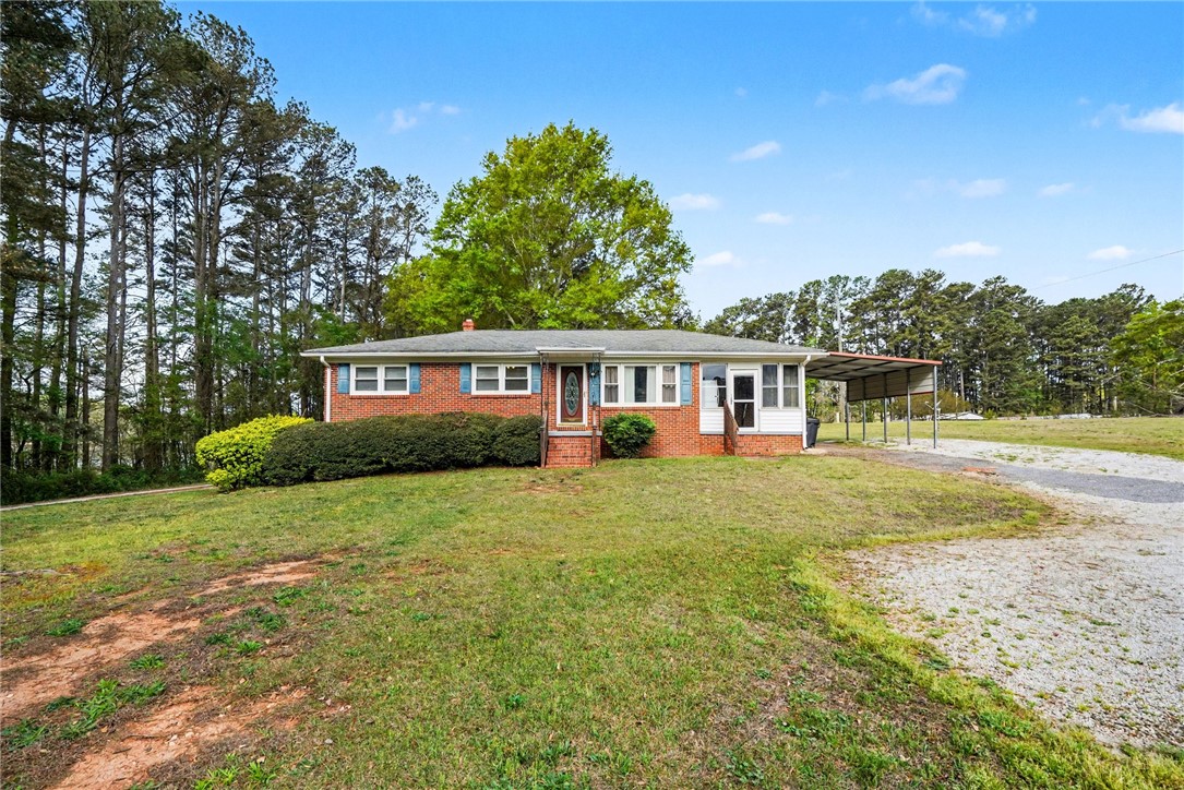 798 Coneross Creek Road Seneca, SC 29678 - Photo 6 of 34 This ranch-style home offers classic charm with a practical carport, nestled amidst a natural, verdant landscape.