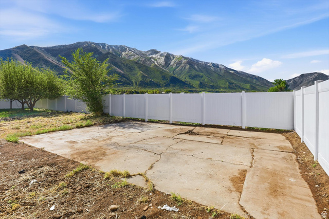 810 East Maple Street Mapleton, UT 84664 - Photo 29 of 49 Rear yard featuring a concrete pad, mature trees, and white privacy fencing