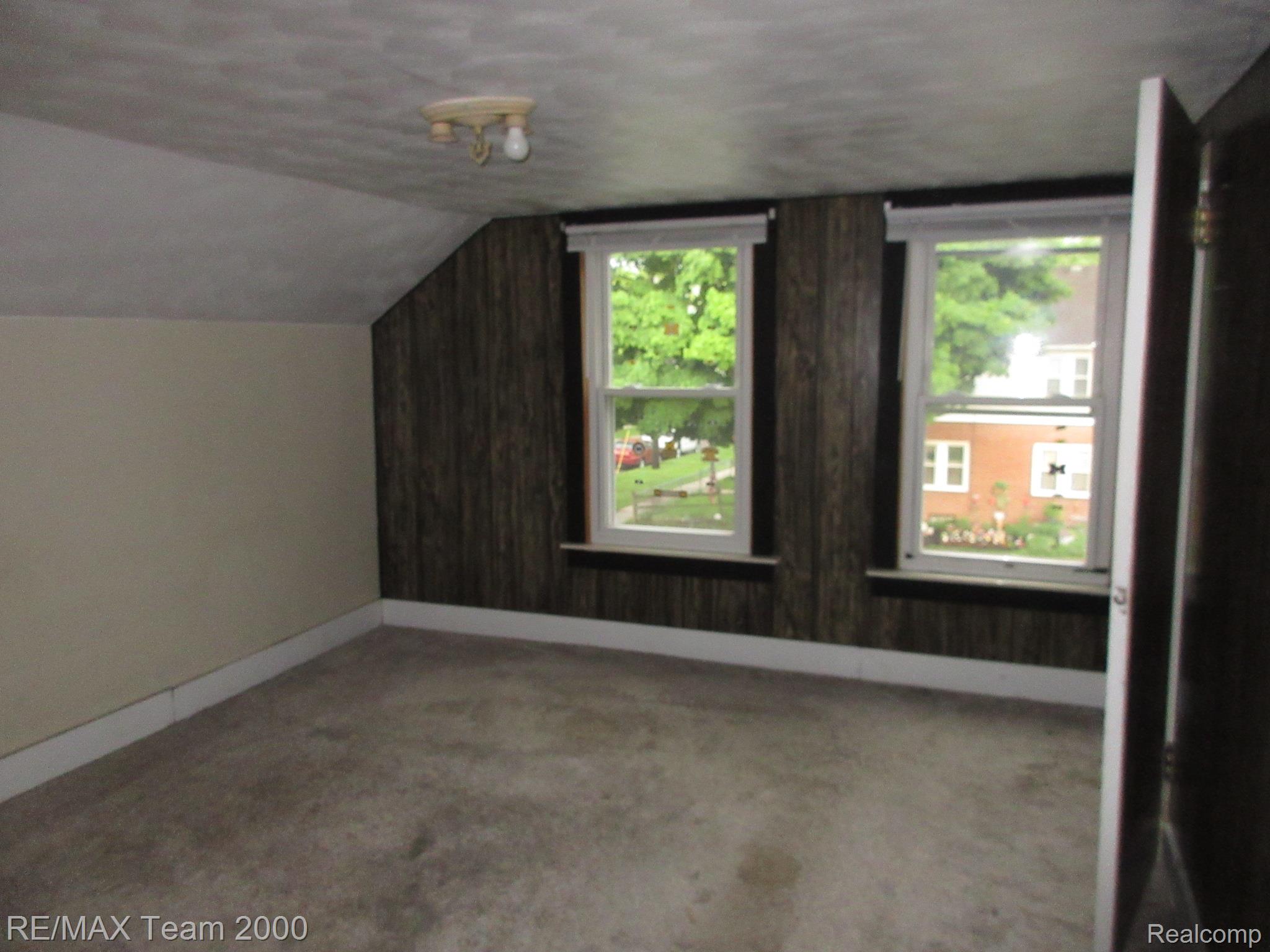 604 Smith Street Monroe, MI 48161 - Photo 19 of 24 Room featuring two windows, dark wood-paneling, a light fixture, and carpeting