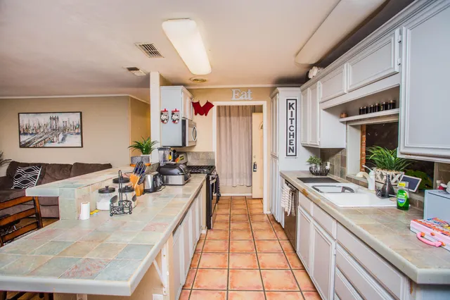 a large kitchen with stainless steel appliances granite countertop a lot of counter space and a sink