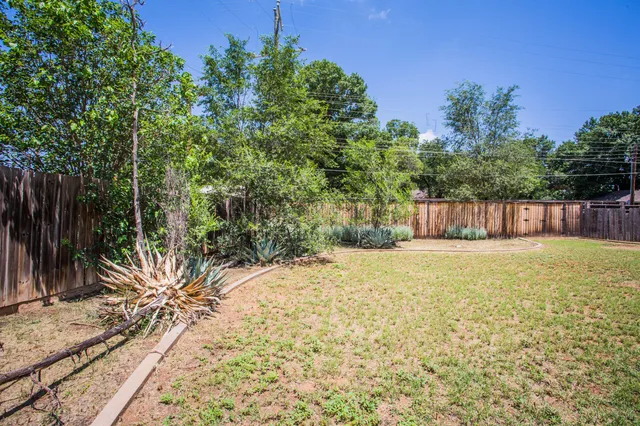 a view of a yard with an tree and wooden fence