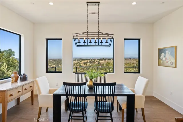 a kitchen with stainless steel appliances a stove a sink dishwasher a oven a dining table and chairs with wooden floor