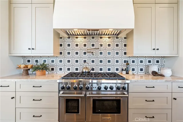 a kitchen with stainless steel appliances granite countertop a stove and white cabinets next to a window