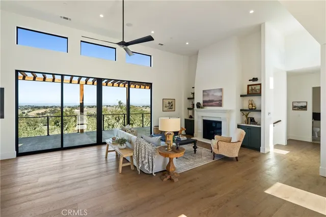 a living room with fireplace furniture large windows and wooden floor