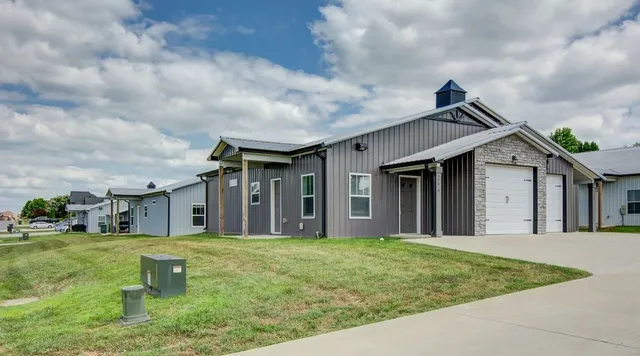 a view of a white house next to a yard with big trees