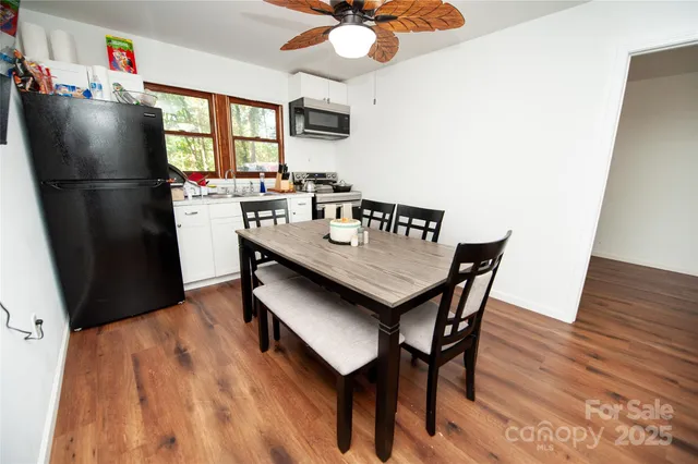a kitchen with stainless steel appliances granite countertop a dining table chairs refrigerator and a sink