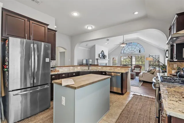a kitchen with stainless steel appliances granite countertop a sink a stove oven a counter space and cabinets
