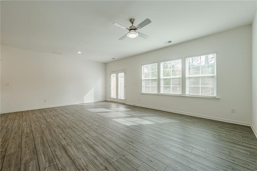 628 Isom Walk Suwanee, GA 30024 - Photo 17 of 39 an empty room with wooden floor and windows