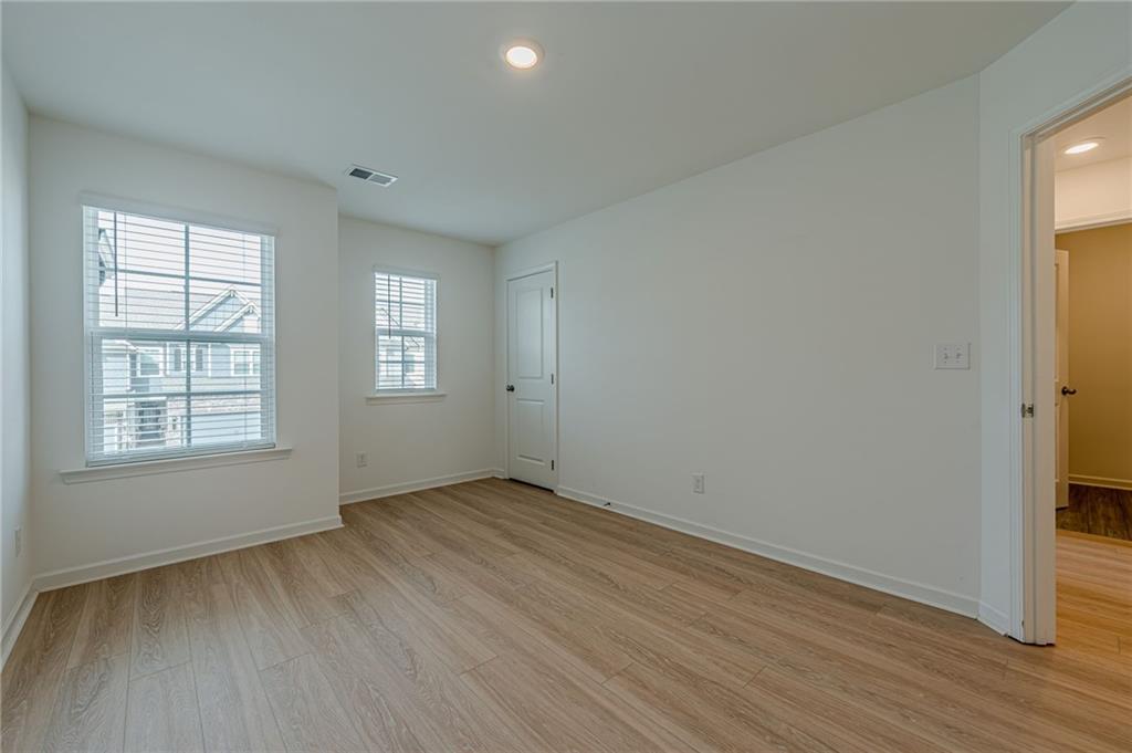 628 Isom Walk Suwanee, GA 30024 - Photo 23 of 39 an empty room with wooden floor and windows