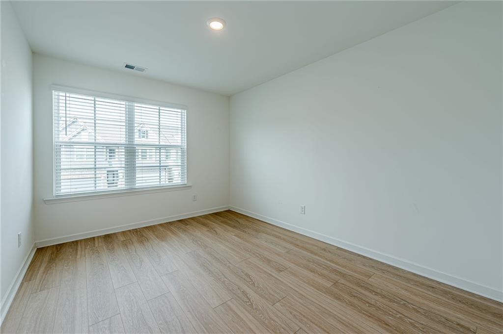 628 Isom Walk Suwanee, GA 30024 - Photo 24 of 39 an empty room with wooden floor and windows