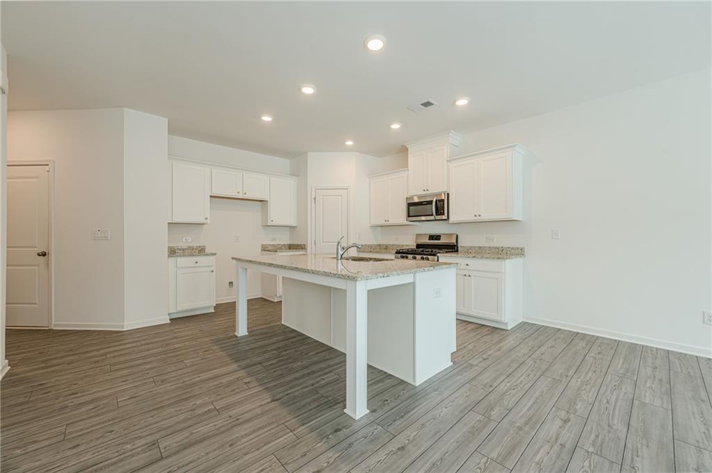 628 Isom Walk Suwanee, GA 30024 - Photo 7 of 39 a kitchen with a refrigerator and white cabinets