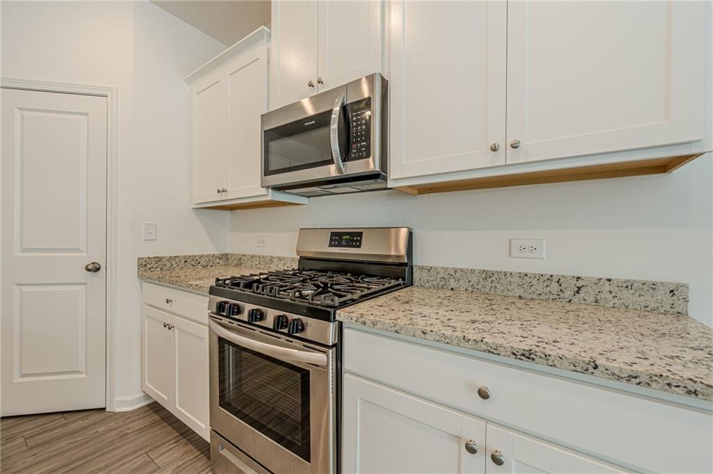 628 Isom Walk Suwanee, GA 30024 - Photo 8 of 39 a kitchen with granite countertop white cabinets and stainless steel appliances