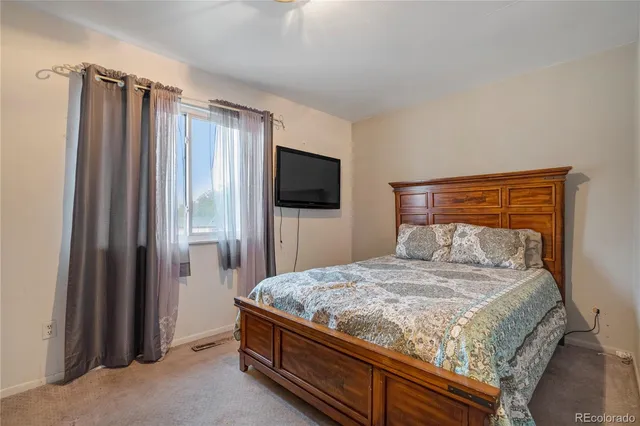 a bedroom with a bed and a flat tv screen on dresser