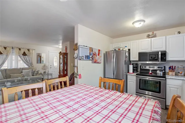 a kitchen with stainless steel appliances kitchen island granite countertop a refrigerator oven a sink dishwasher and white cabinets with wooden floor