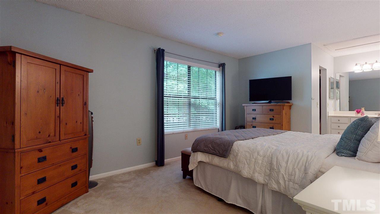7744 Falcon Rest Circle Raleigh, NC 27615 - Photo 12 of 22 a bedroom with a bed and a flat tv screen on dresser